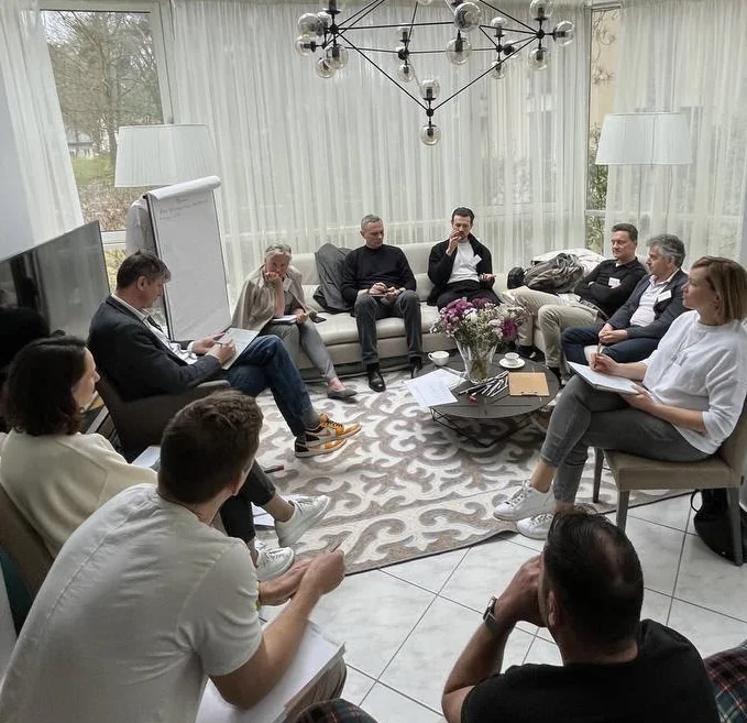 A group seated in a circle with notebooks during a discussion in a bright lounge